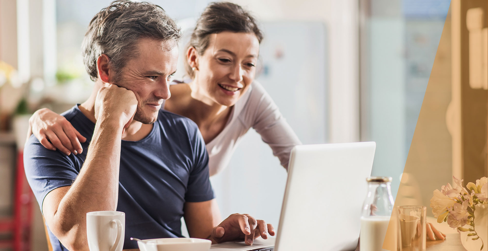 middle aged couple looking at a laptop in their kitchen